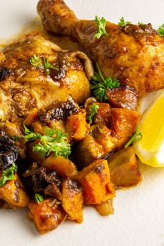 a plate with chicken, potatoes and lemon wedges on the side for garnish