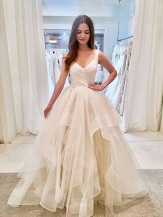 a woman standing in front of a white curtain wearing a dress with ruffled layers