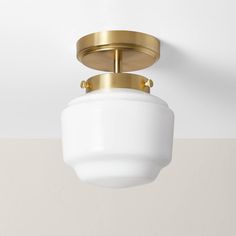 a light fixture with a white glass shade on the bottom and gold trim around it