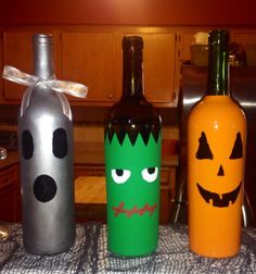 three wine bottles decorated to look like halloween characters