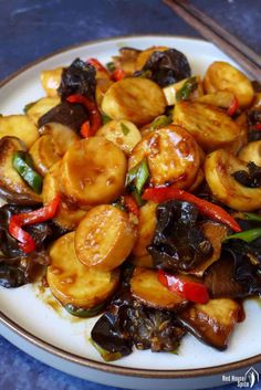 a white plate topped with fried vegetables on top of a blue tablecloth next to chopsticks