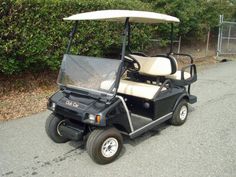 a black and white golf cart parked on the side of the road next to bushes