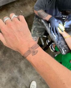 a person with a tattoo on their wrist holding onto another persons hand and wearing gloves