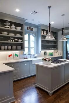 a large kitchen with wooden floors and gray cabinets