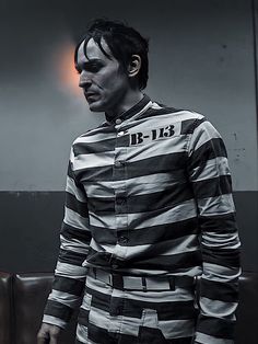 a man dressed in jail clothes standing next to a wall