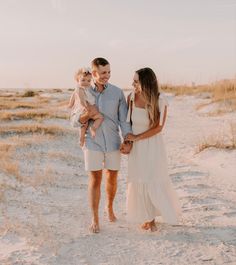 a man, woman and child are walking on the beach with their arms around each other