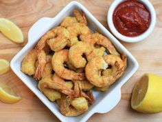 there is a bowl of shrimp next to a lemon and ketchup