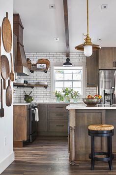 a kitchen with wood floors and white brick walls, an island in the middle has a bowl of fruit on it