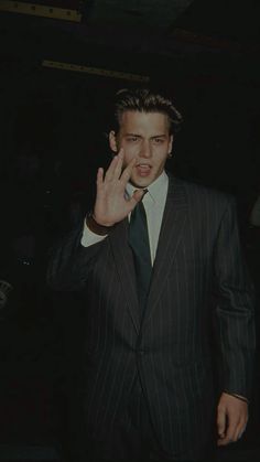 a man in a pinstripe suit is holding his hand up to his face