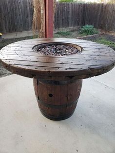 a wooden barrel sitting on top of a cement floor next to a fence and tree