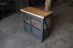 a kitchen island made out of metal and wood with mesh doors on the sides, in a warehouse