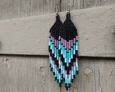 a pair of beaded earrings hanging on a wooden door with beads in the shape of an owl