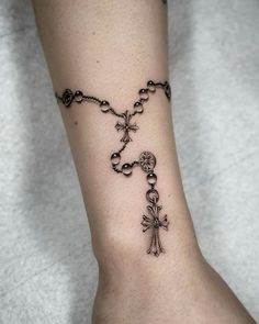 a woman's foot with a rosary and cross tattoo on the side of her leg