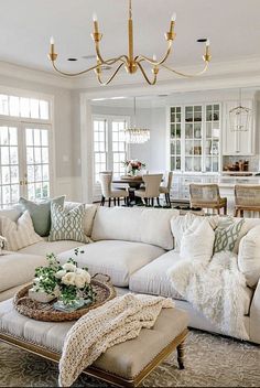 a living room filled with lots of furniture and a chandelier hanging from the ceiling