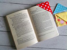 an open book sitting on top of a wooden table next to two folded handkerchiefs