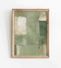 a painting hanging on the wall in front of a white wall with a wooden frame