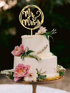 a wedding cake with pink flowers and greenery on top