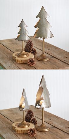 three metal christmas trees sitting on top of a wooden table next to a pine cone