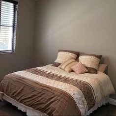 a bed sitting in a bedroom next to a window with blinds on top of it