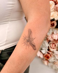 a woman's arm with a tattoo on it that has a bird flying in the sky