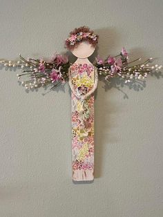 a wooden cross with flowers on it and an angel's head hanging from the wall