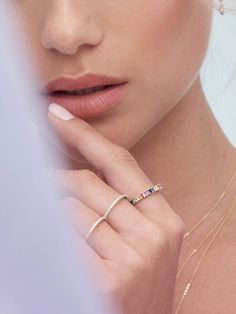 a close up of a woman wearing a gold ring and necklace with multicolored stones