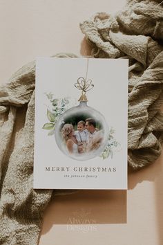 an ornament hanging from a blanket on top of a card that says merry christmas