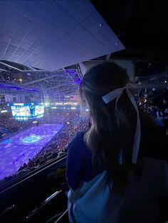 a woman is looking at an ice rink in the middle of a stadium with purple lights