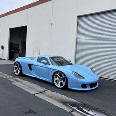 a blue sports car parked in front of a building