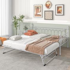 a metal bed frame with two pillows on top of it in a room next to a potted plant