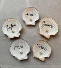 four scallop shells with names on them