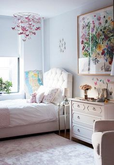 a bedroom with white furniture and flowers on the wall hanging from the ceiling above the bed