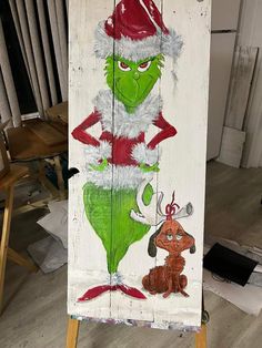 a wooden sign with the grinch on it's face and santa claus hat