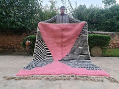 a man sitting on top of a pink and black blanket