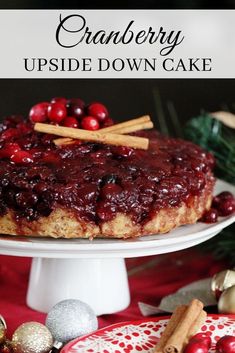 cranberry upside down cake on a plate with cinnamon sticks and christmas decorations around it