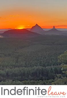 the sun is setting over some mountains and trees