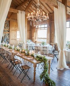 a long table is set up in the middle of a room with white drapes