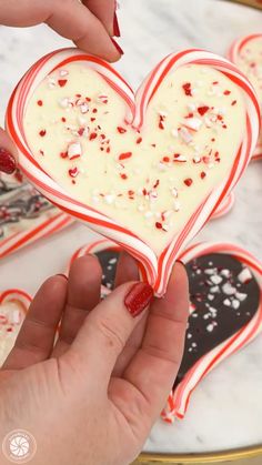 someone is decorating some heart shaped cookies with candy canes and sprinkles