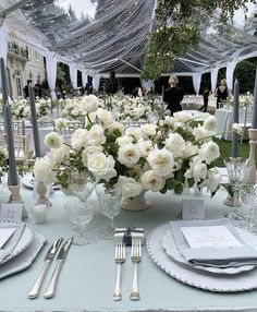 the table is set with white flowers and silverware