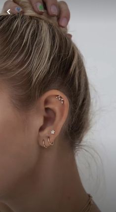 a close up of a woman's ear with two piercings on it and one behind her ear