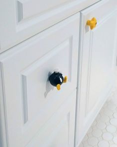 two black and yellow knobs on white cabinets