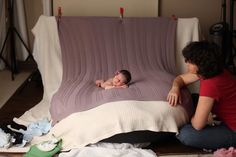 a woman sitting next to a baby on top of a bed