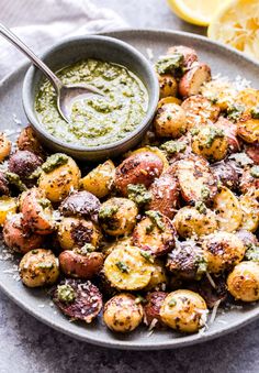 roasted potatoes with pesto sauce in a bowl on a plate next to lemon wedges