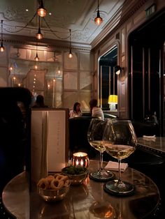 two wine glasses sitting on top of a table next to a box of donuts