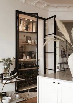 a white vase filled with lots of flowers on top of a counter next to a wine rack