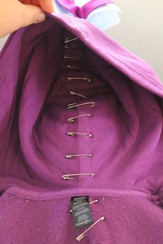 someone is sewing on the back of a purple jacket with pins and needles attached to it