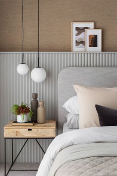 a bed room with a neatly made bed and two hanging lights