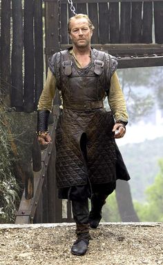 a man dressed in armor walking across a bridge