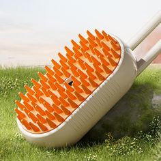 a large orange brush sitting on top of a green field