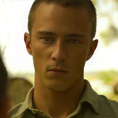 a close up of a person wearing a green shirt and looking at someone in the distance